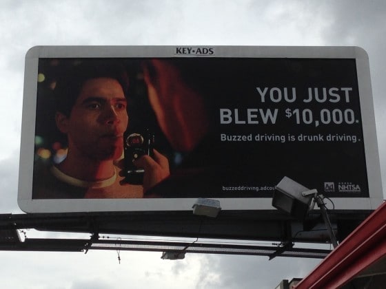 Breathalyzer machine on a billboard. The advertisement highlights the significant financial consequences of a DUI conviction, estimating costs at roughly $10,000.
