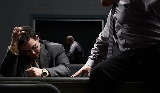 Police interrogation room. A police officer is questioning a suspect in a room with a table and chairs.